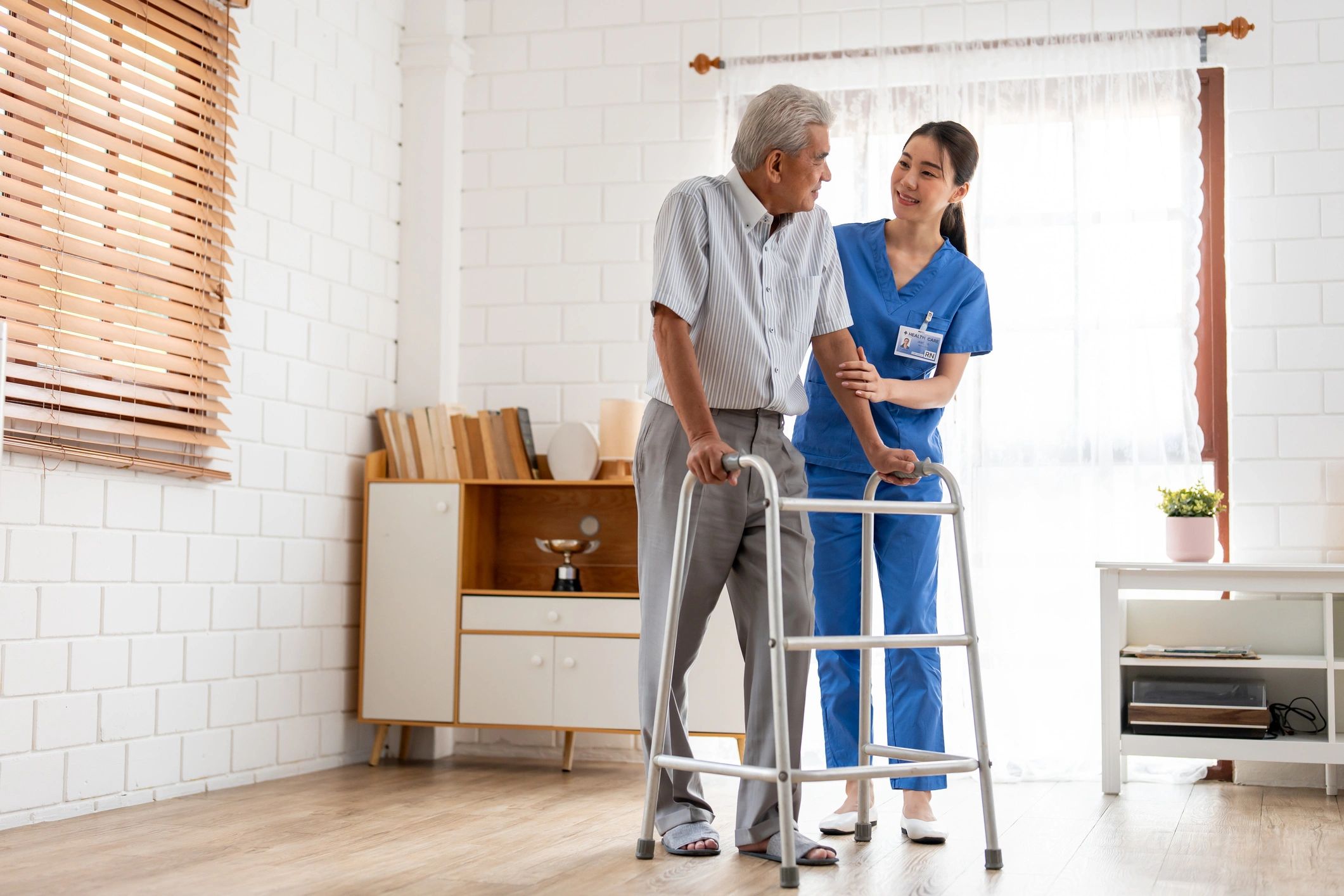Healthcare worker assisting elderly man with walker