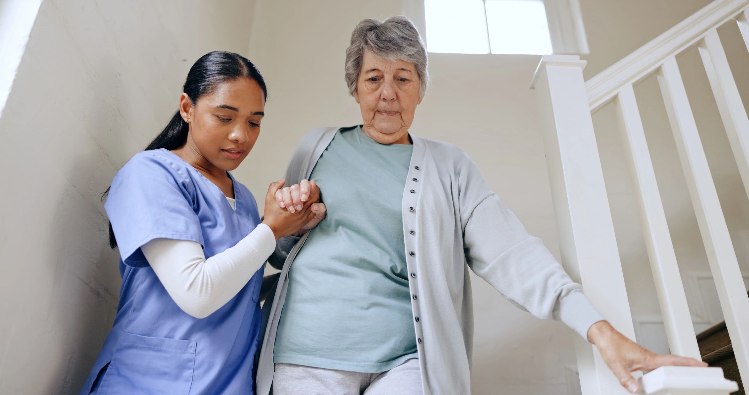 Caregiver assisting elderly woman on stairs
